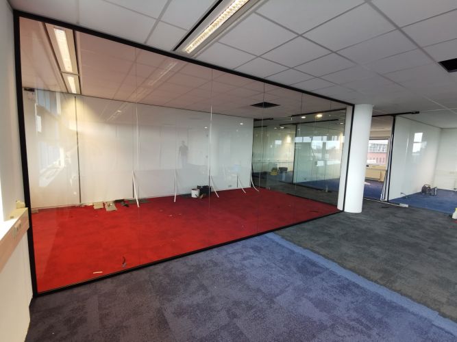 Glaswand met zwarte profielen en pendeldeuren