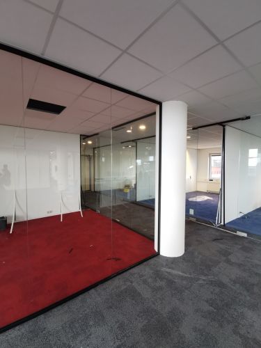 Glaswand met zwarte profielen en pendeldeuren